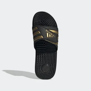 Sandalias Adidas Adissage negras con detalles dorados, diseño clásico y plantilla con masajeadores para máxima comodidad.